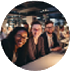 Three people sitting together indoors, smiling towards the camera in a social setting.